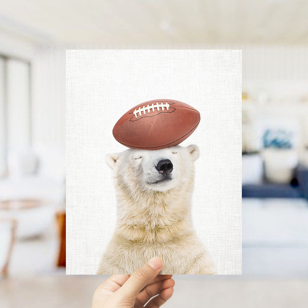 A polar bear is standing on its head with a football on top of it, creating a humorous and playful scene.