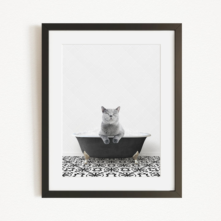 A gray cat sitting in a black bathtub, with a patterned tile floor in the foreground.