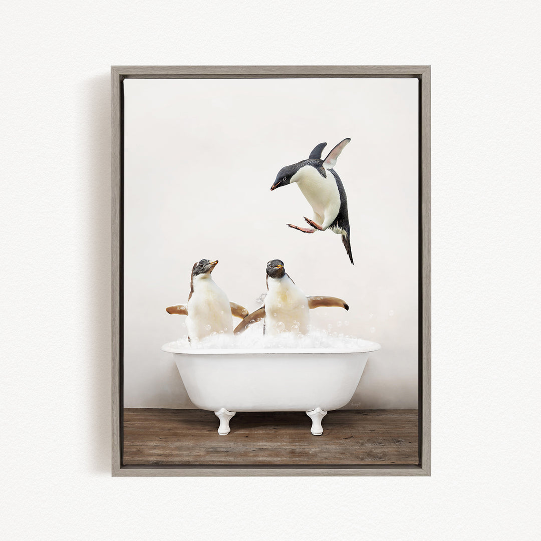 A framed image depicting two penguins standing in a white bathtub filled with bubbles, with one penguin flying towards the other.