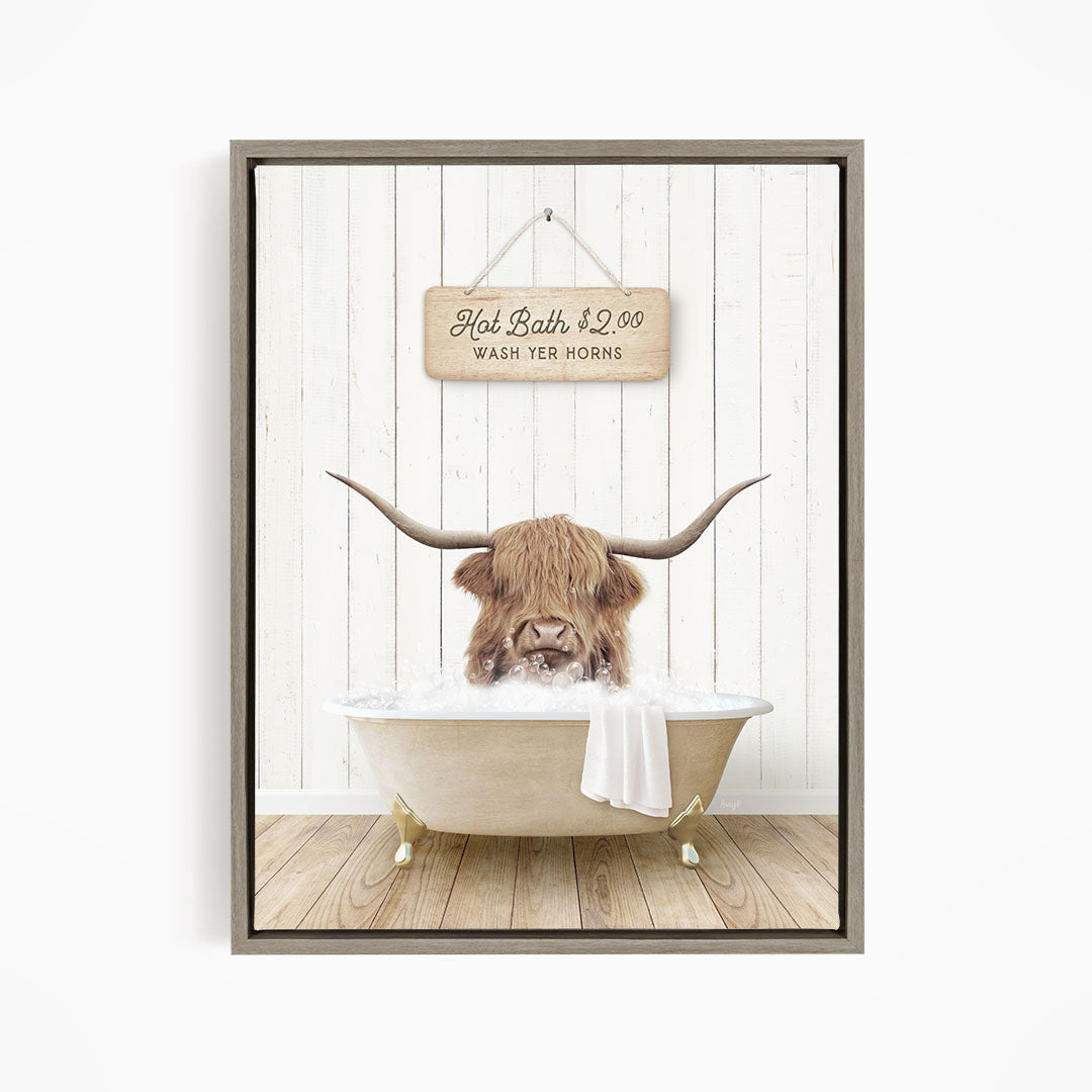 A framed image depicting a Highland cow with long horns sitting in a bathtub, with a sign above the bathtub that reads "Hot Bath $2.00 WASH YER HORSES".
