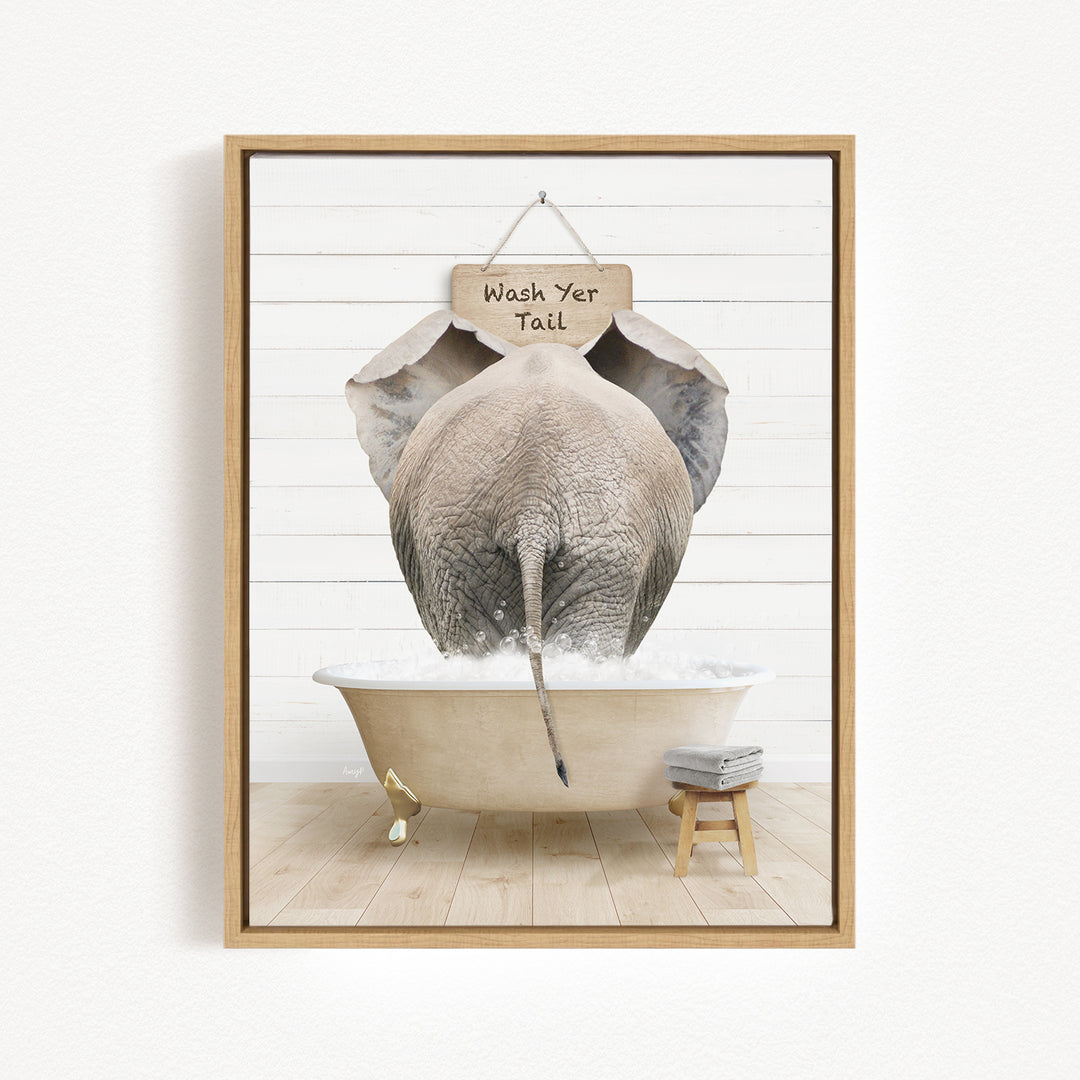 A framed image depicting an elephant standing in a bathtub filled with water, with a sign above it that says "Wash Your Tail".