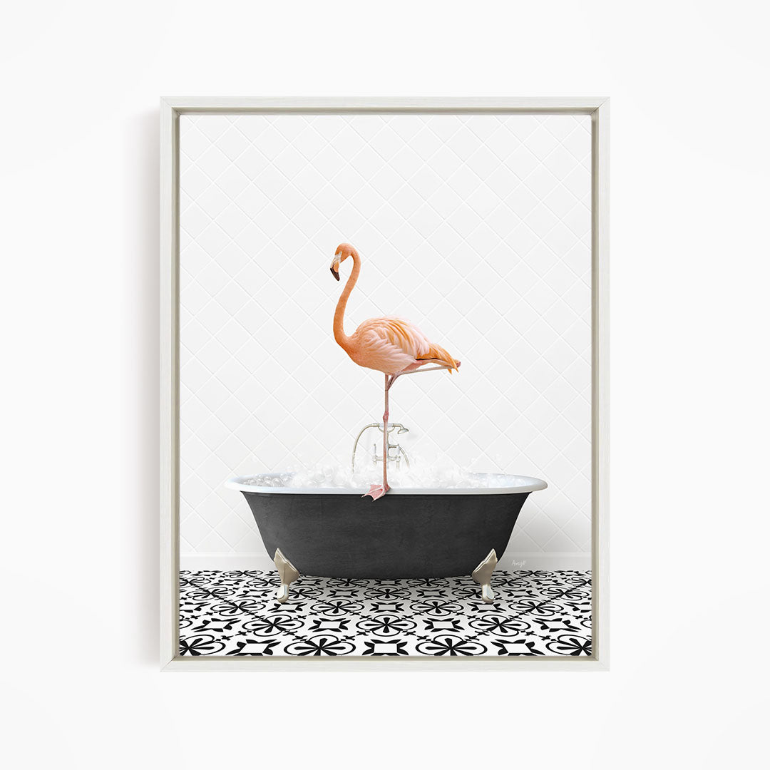 A pink flamingo standing on one leg in a black bathtub filled with water, set against a white tiled wall.