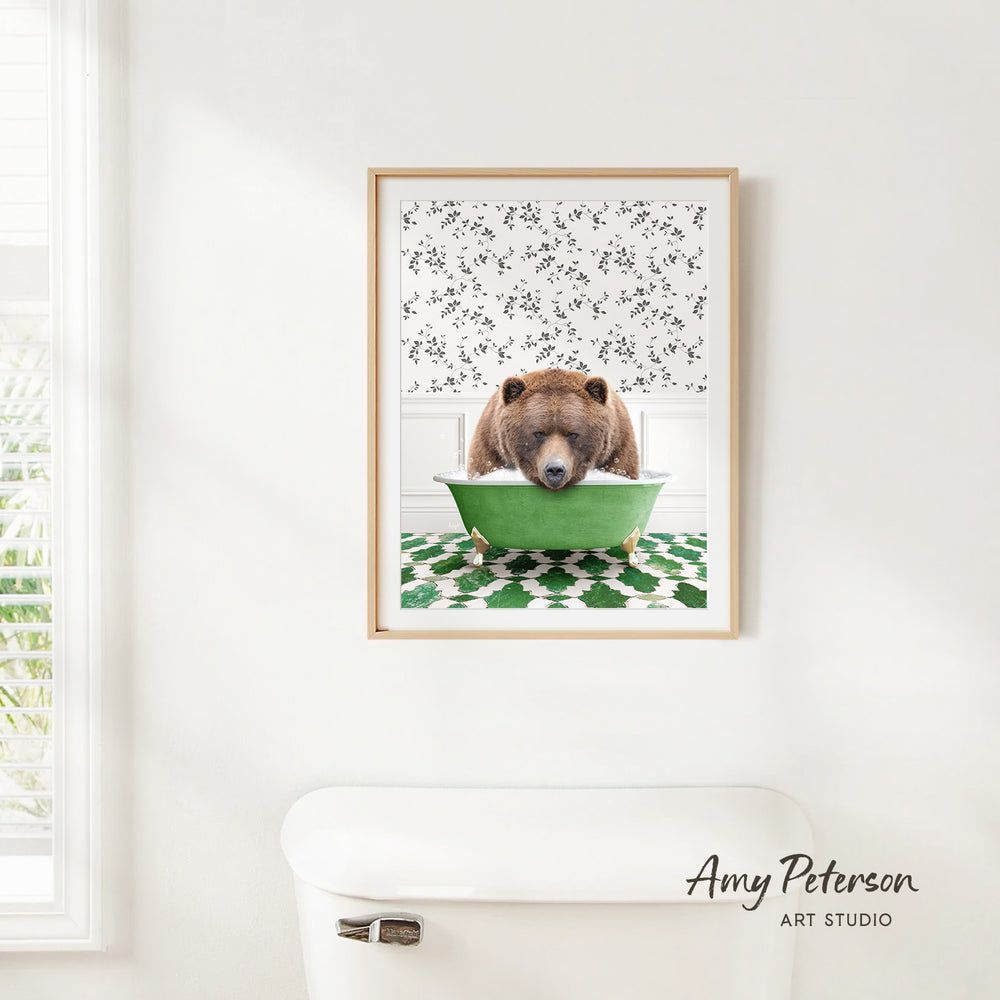 A framed image of a brown bear sitting in a green bathtub, with a patterned wall behind it.