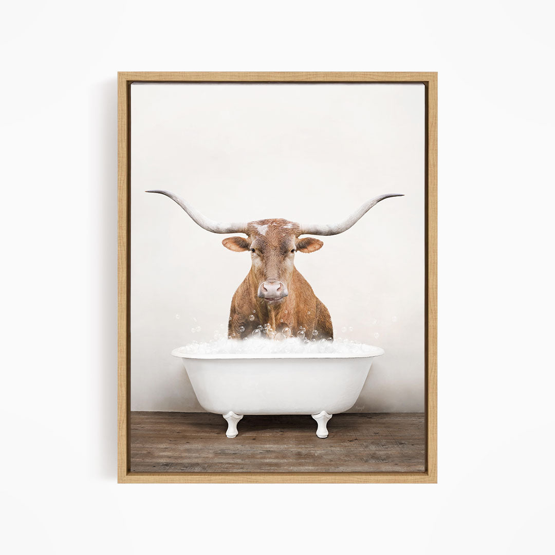 A brown cow with long horns is standing in a white bathtub filled with water, creating a whimsical and humorous scene.