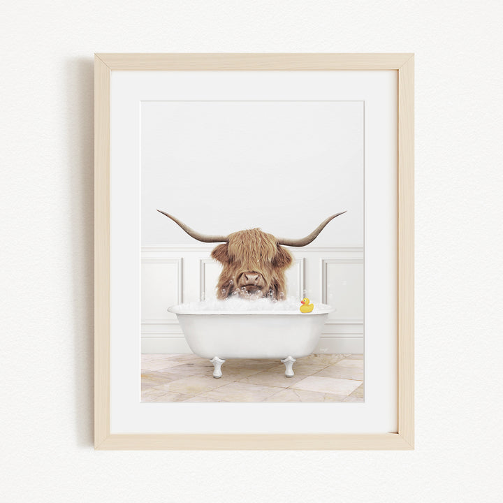 A Highland cow with large horns is sitting in a white bathtub, surrounded by a yellow rubber duck.