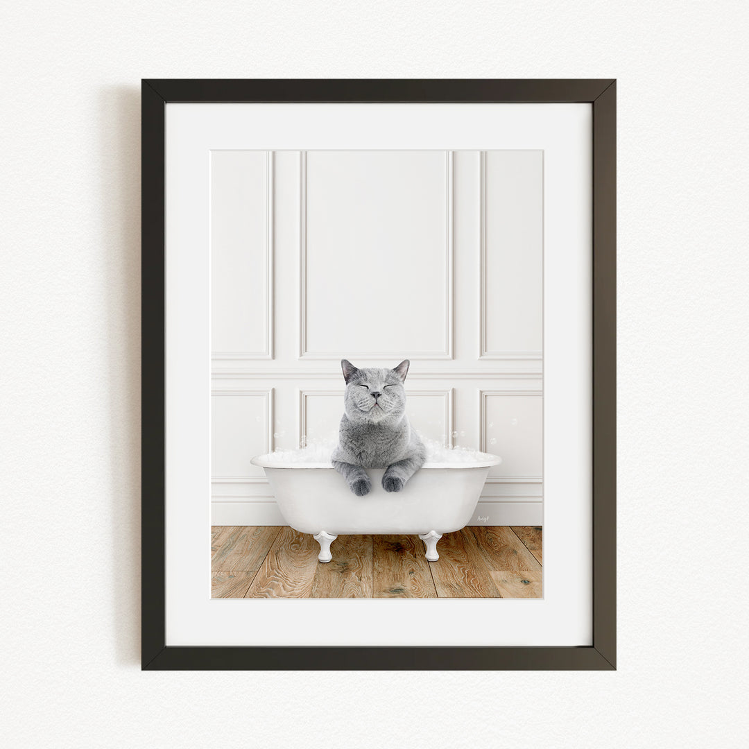 A gray cat sitting in a white bathtub, with a wooden floor in the background.