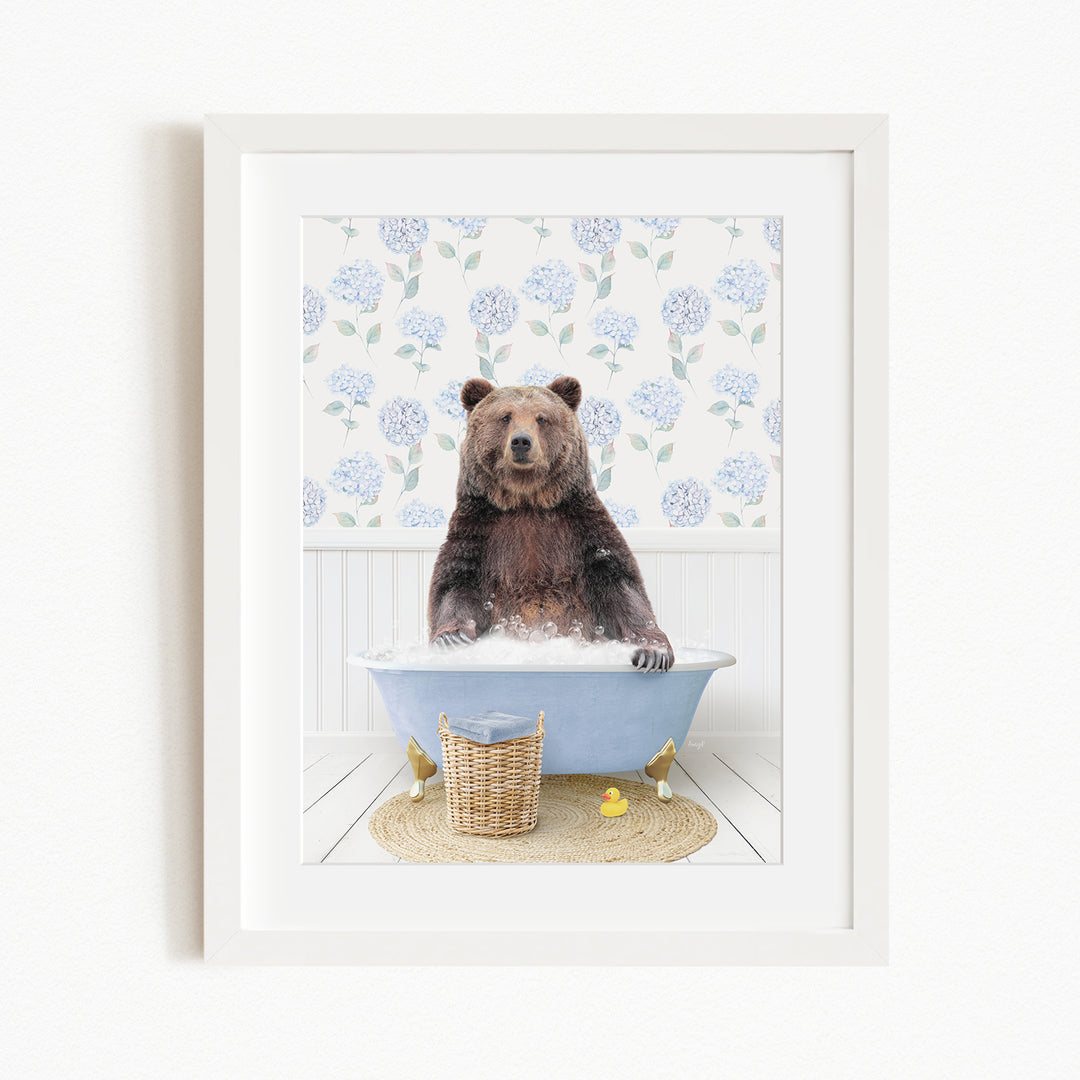 A brown bear sitting in a blue bathtub filled with water, surrounded by a floral patterned wall and a basket of rubber ducks.