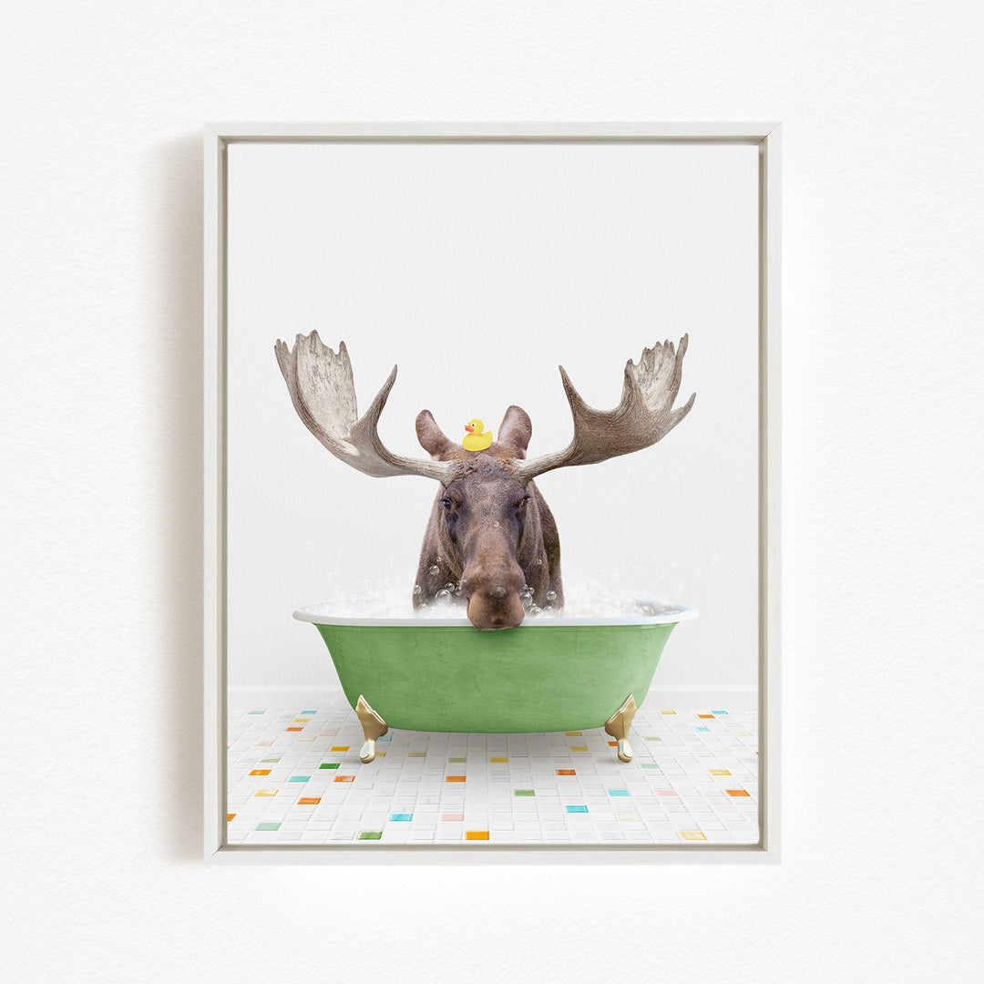 A moose with large antlers is sitting in a green bathtub, with a rubber duck perched on its head.