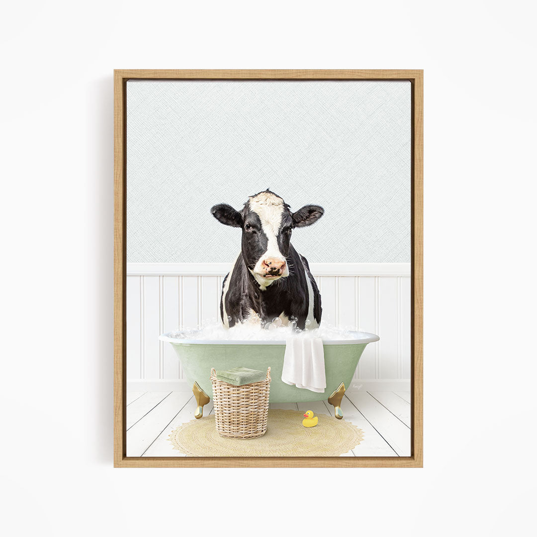 A black and white cow is sitting in a green bathtub filled with water, surrounded by a basket of toys and a yellow rubber duck.