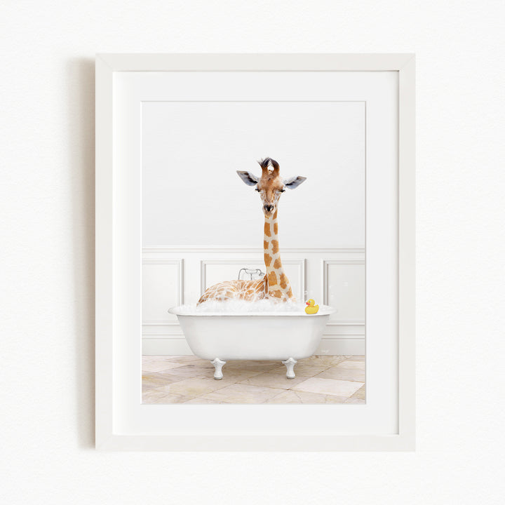 A giraffe is sitting in a white bathtub filled with water, surrounded by bubbles, with a yellow rubber duck floating nearby.
