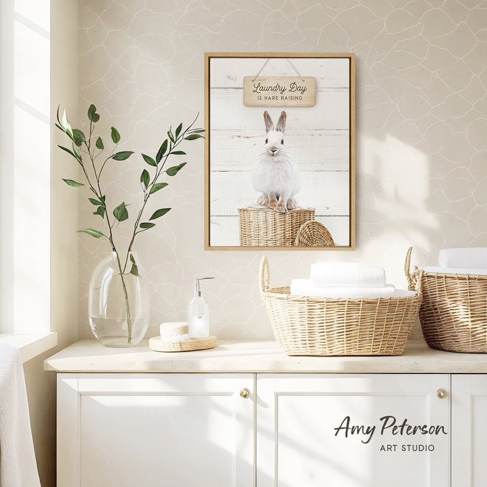 a bathroom with a framed picture of a rabbit on the wall, a vase with a plant, and baskets on a counter.