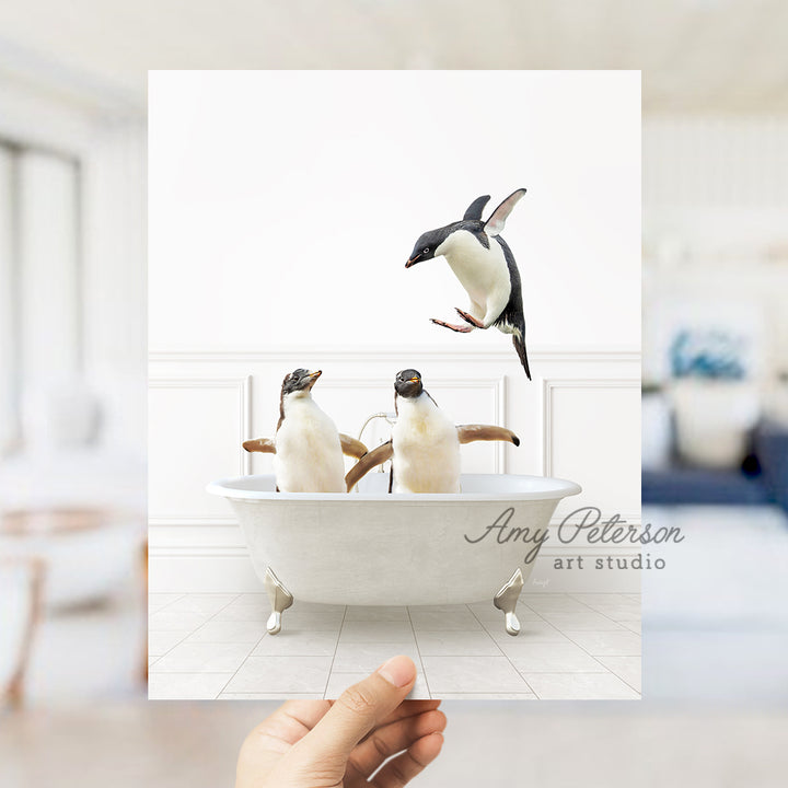 a hand holding a card with three penguins in a bathtub