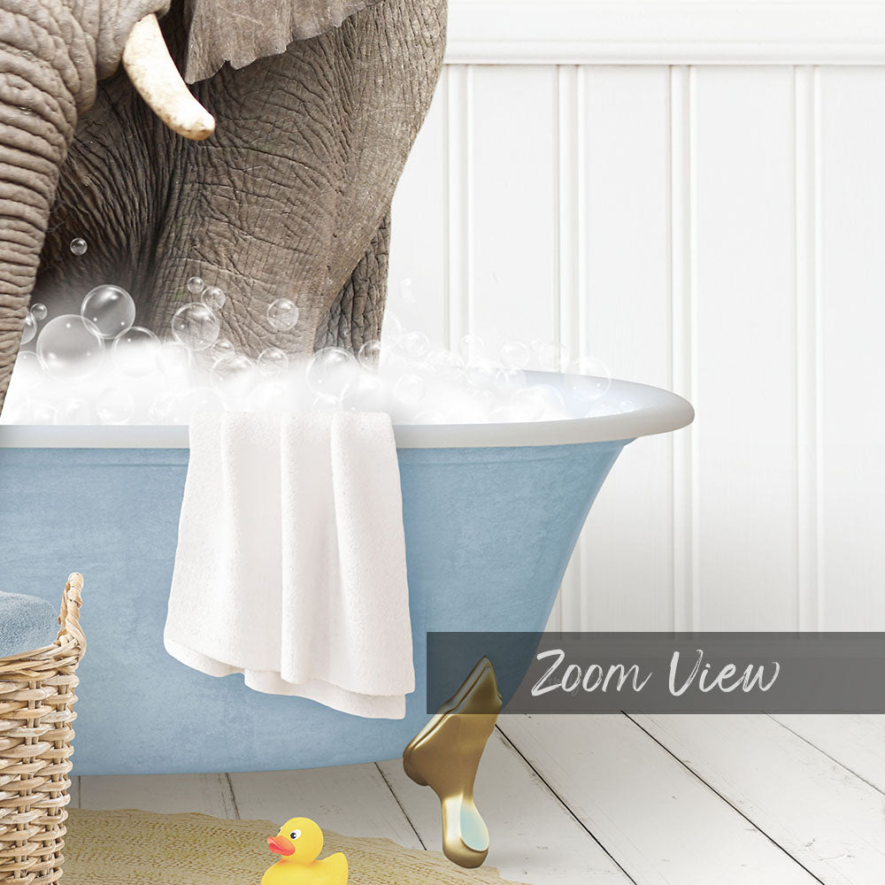 A large elephant is standing in a blue bathtub filled with bubbles, surrounded by a yellow rubber duck and a white basket.