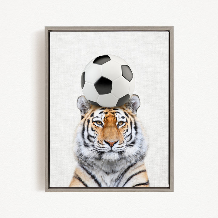 A tiger is sitting on a soccer ball, creating a playful and whimsical scene.