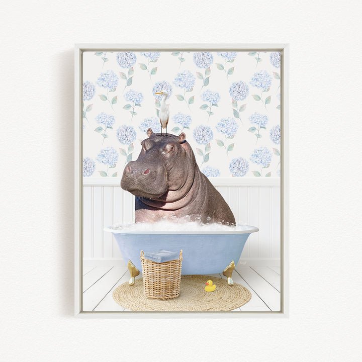 A hippopotamus sitting in a bathtub filled with water, surrounded by a wicker basket, a yellow rubber duck, and a white wall with blue floral wallpaper.