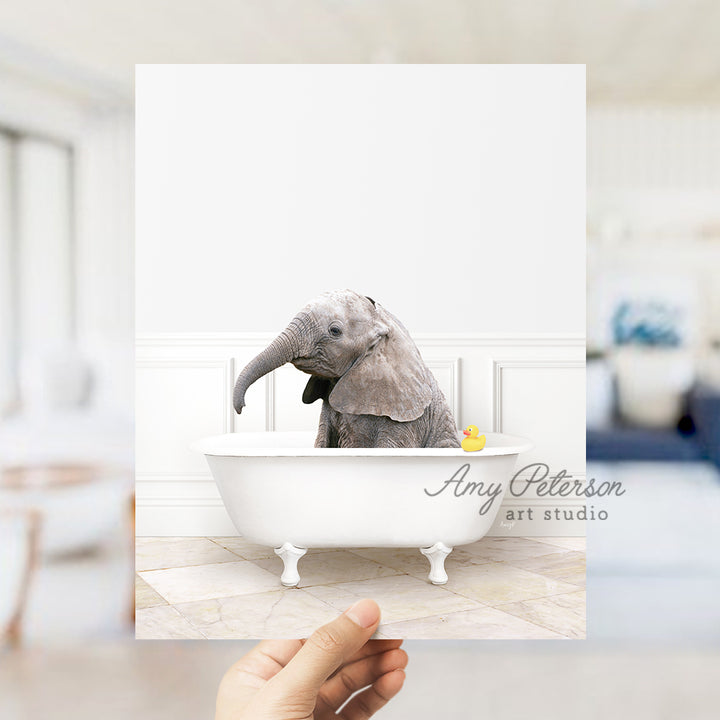 a person holding up a picture of an elephant in a bathtub