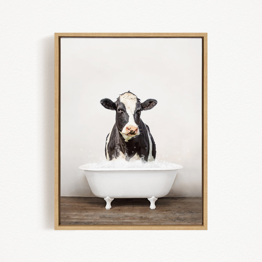 A black and white cow standing in a white bathtub filled with water, creating a whimsical and humorous scene.