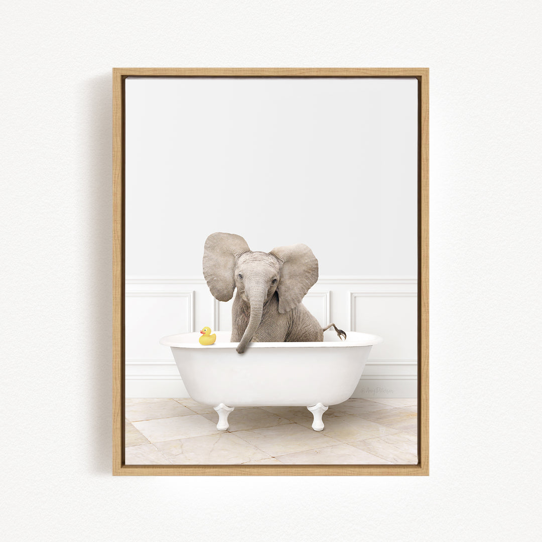 A baby elephant sitting in a white bathtub, with a yellow rubber duck floating in the water.