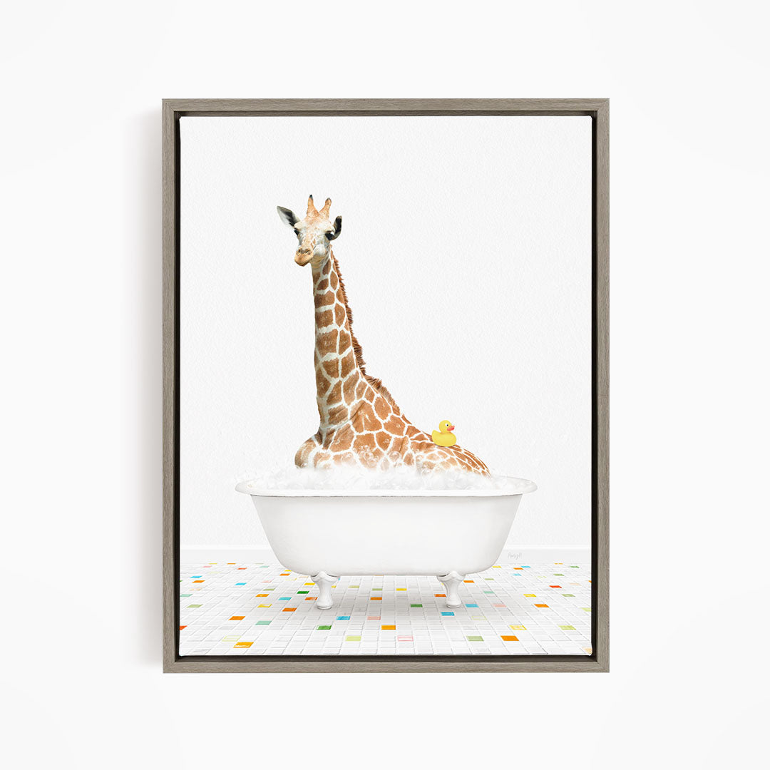 A giraffe is sitting in a white bathtub filled with bubbles, with a yellow rubber duck floating on the water.