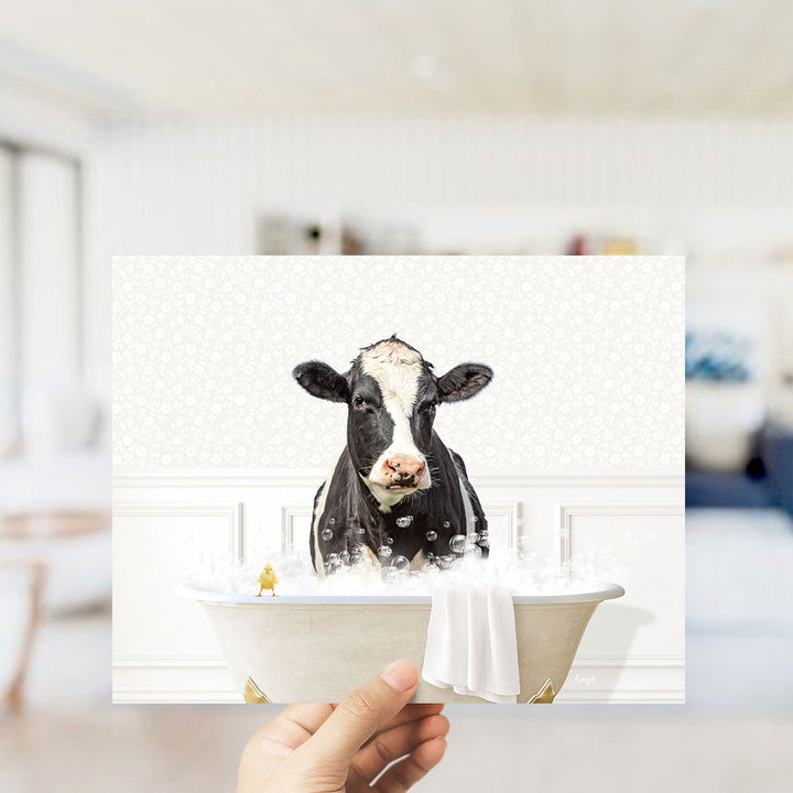A black and white cow is sitting in a bathtub filled with bubbles, with a small yellow bird perched on the edge of the tub.