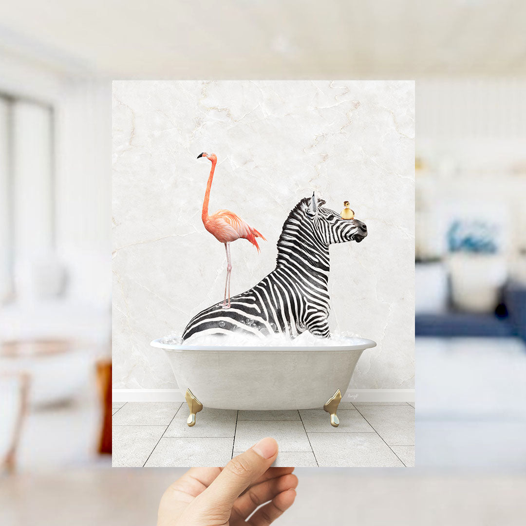 A hand holds up a framed image depicting a zebra sitting in a bathtub, with a flamingo standing on its back.