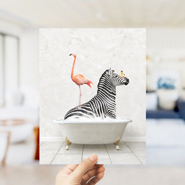 A hand holds up a framed image depicting a zebra sitting in a bathtub, with a flamingo standing on its back.
