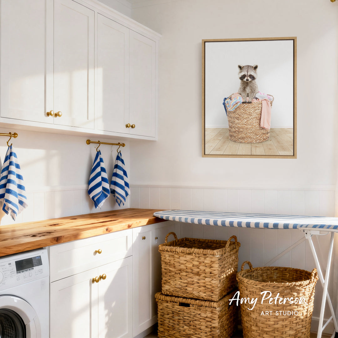 A laundry room with white cabinets, a wooden countertop, and a framed picture of a raccoon sitting in a basket.
