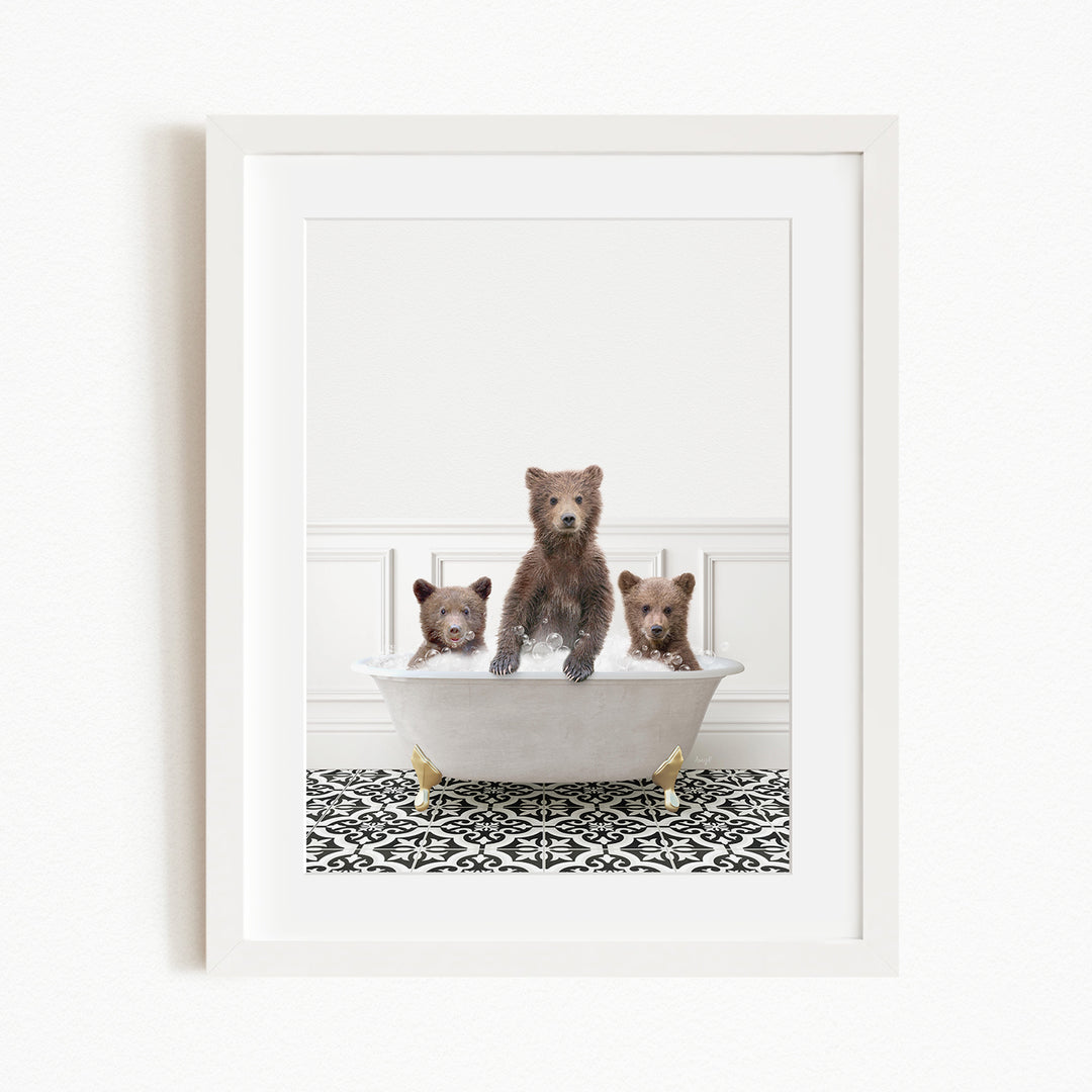 A framed image depicting three brown bears sitting in a white bathtub, with a black and white patterned floor beneath them.