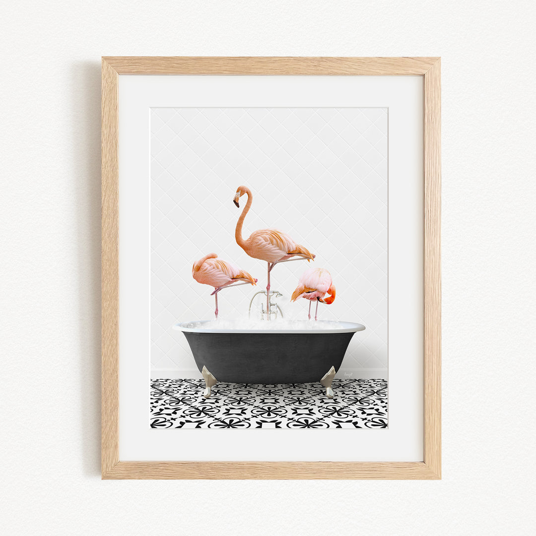 A framed image depicting three flamingos standing in a bathtub filled with water.