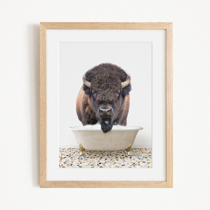 A buffalo with large horns is standing in a white bathtub filled with water, creating a playful and whimsical scene.