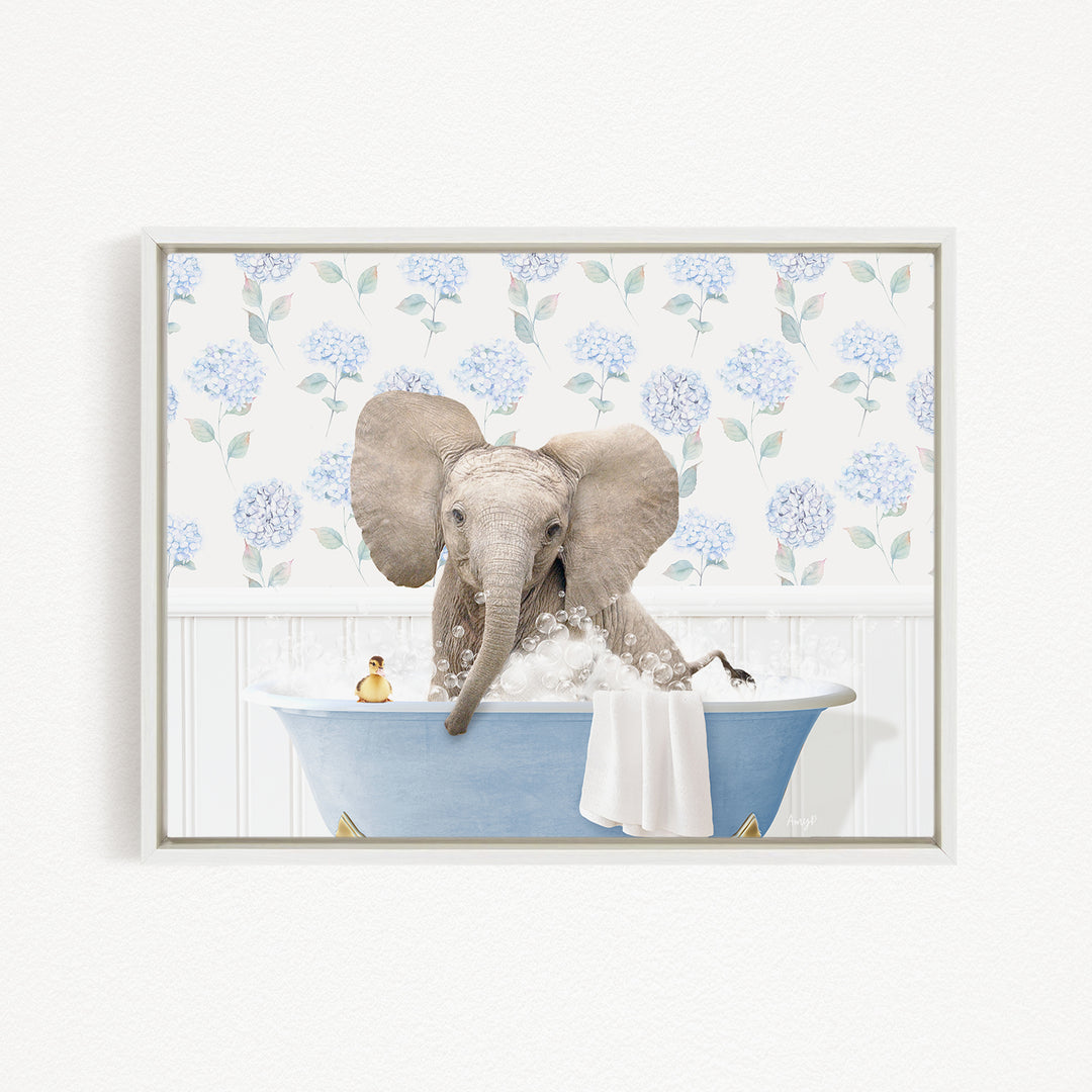 A gray elephant is sitting in a blue bathtub filled with water, surrounded by a floral pattern on the wall behind it.