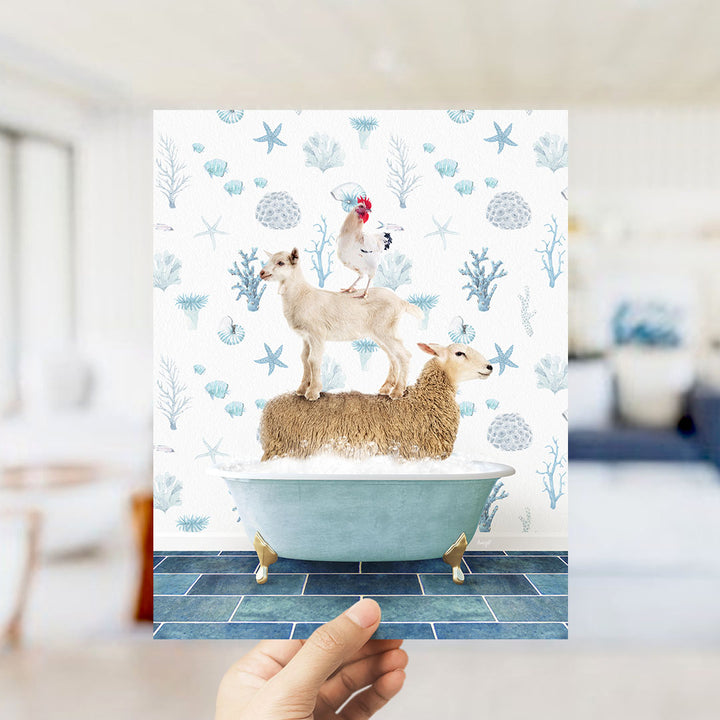 A hand is holding up a print featuring a whimsical scene of a goat standing on a sheep in a bathtub, surrounded by a blue and white floral pattern.