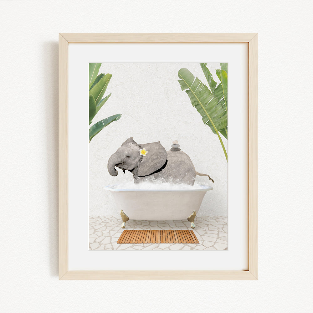 A framed image depicting a baby elephant sitting in a bathtub filled with water, surrounded by tropical plants.