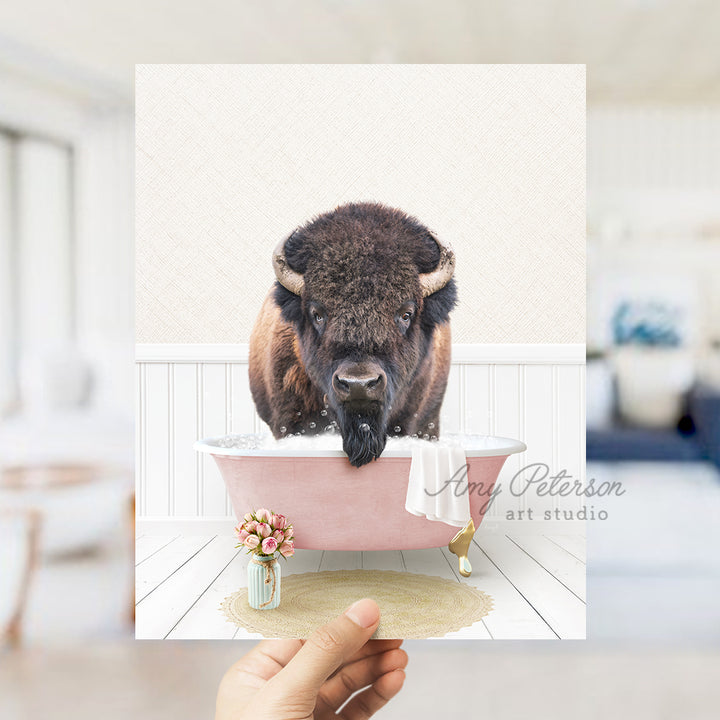 a person holding up a picture of a bison in a bathtub