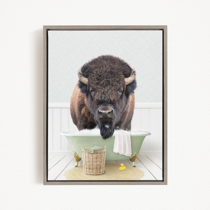 A buffalo with a long beard is sitting in a green bathtub, surrounded by a basket, a yellow rubber duck, and a towel.
