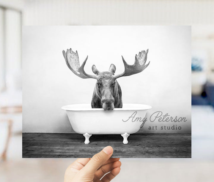 a person holding up a picture of a moose in a bathtub