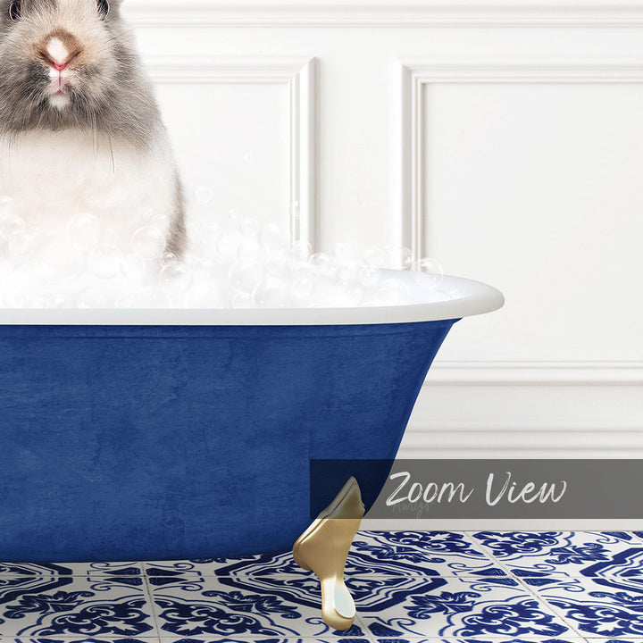 A fluffy gray and white rabbit sitting in a blue bathtub filled with bubbles, with a white wall and a patterned tile floor in the background.
