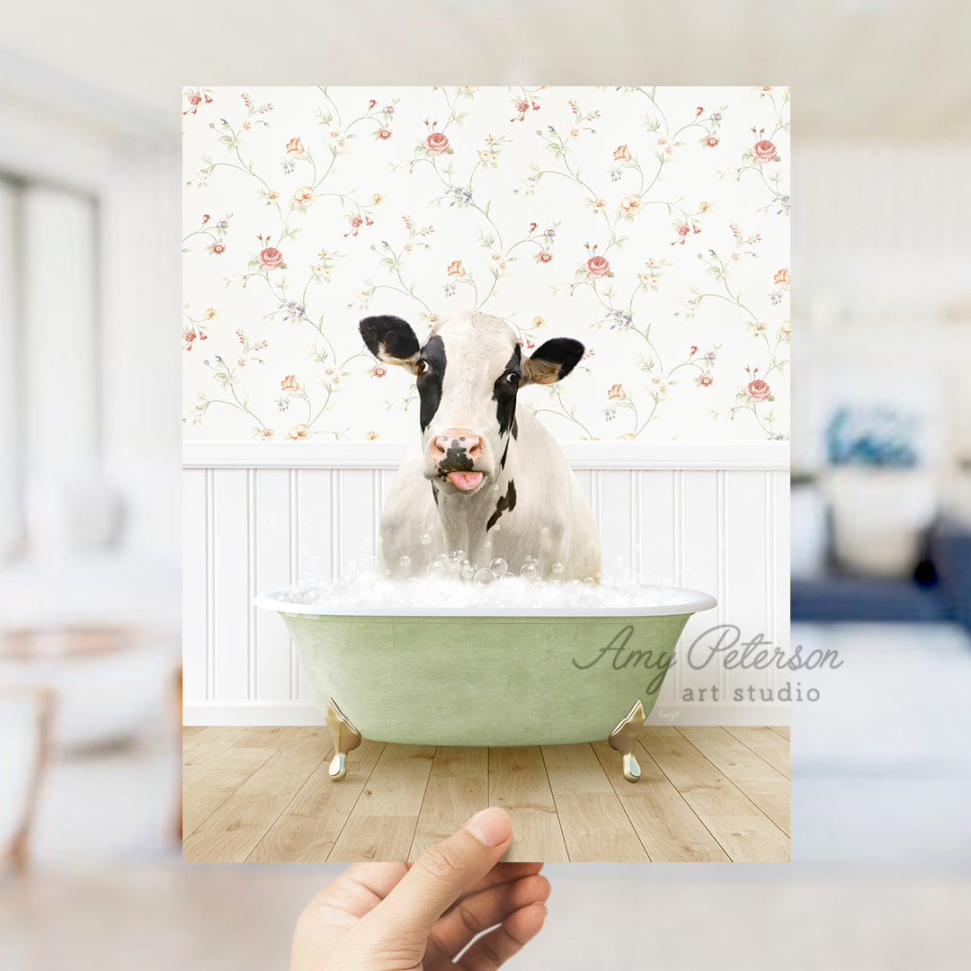 a hand holding up a picture of a cow in a bathtub