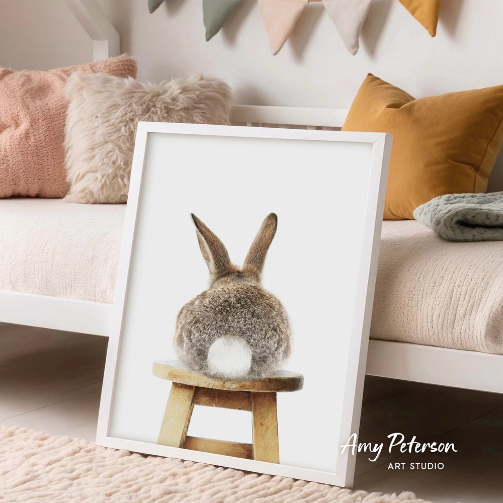 A framed image of a rabbit sitting on a wooden stool, with a cozy and inviting atmosphere in the background.