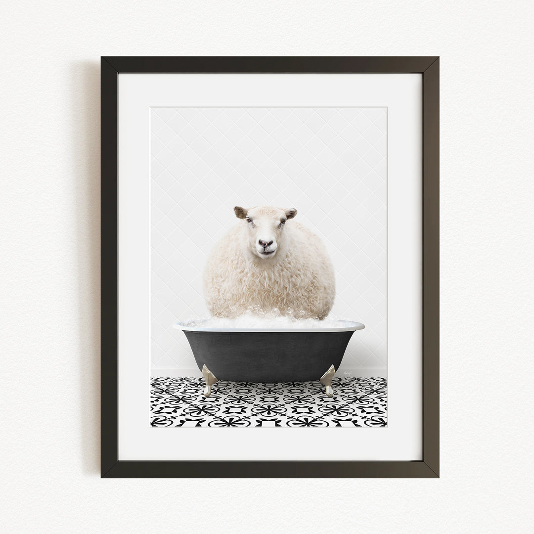 A fluffy white sheep sits in a black bathtub filled with bubbles, surrounded by a black and white patterned tile floor.