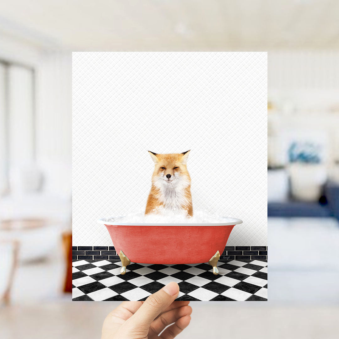 A hand holds up a framed image of a fox sitting in a red bathtub filled with bubbles, against a black and white checkered floor.