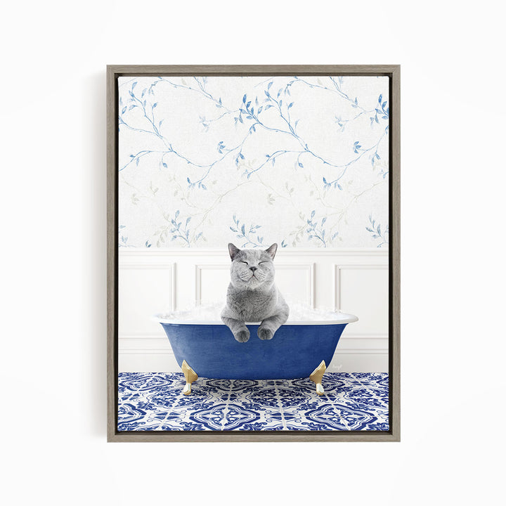 A gray cat sitting in a blue bathtub filled with bubbles, with a patterned tile floor and a floral wallpaper in the background.