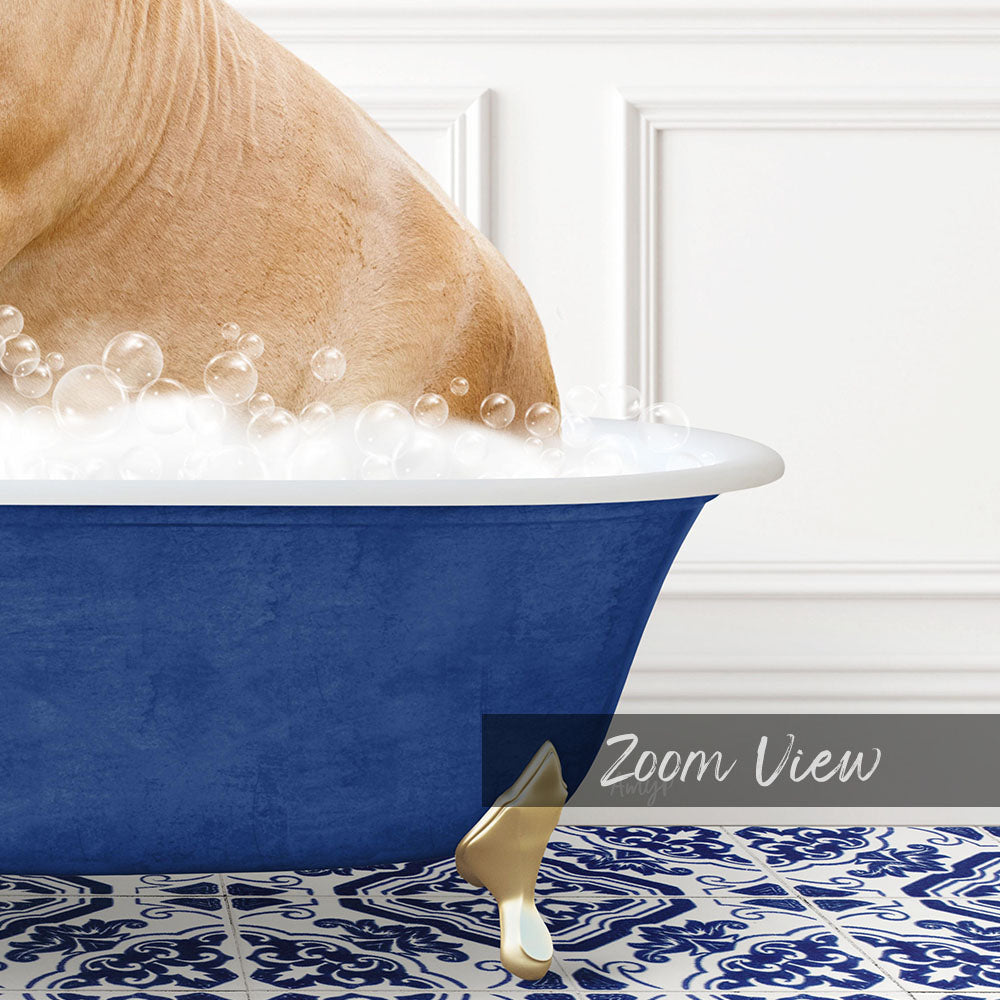A dog is sitting in a blue bathtub filled with bubbles, with a gold claw-like object resting on the edge of the tub.