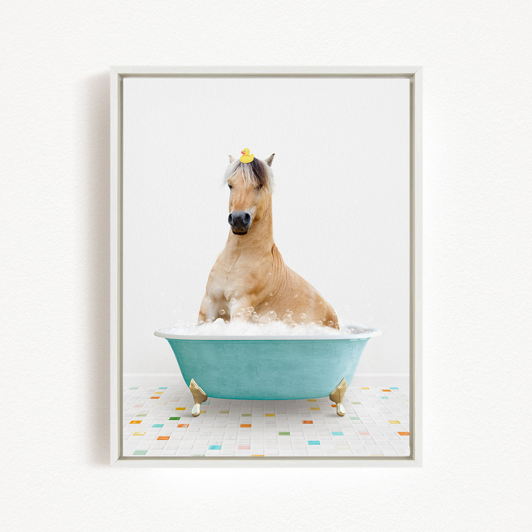 A light brown horse is sitting in a blue bathtub filled with bubbles, with a yellow rubber duck on its head.