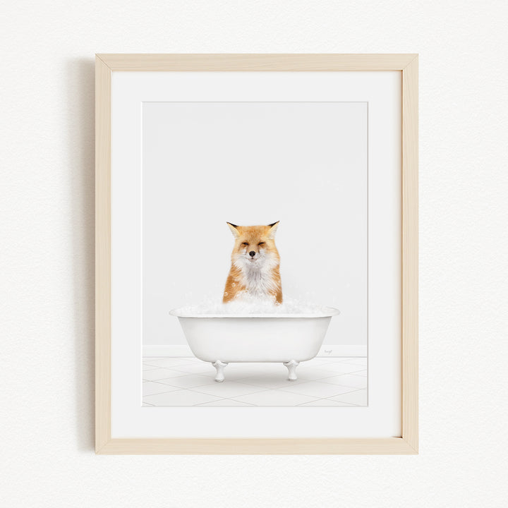A red fox is sitting in a white bathtub filled with bubbles, looking directly at the camera.