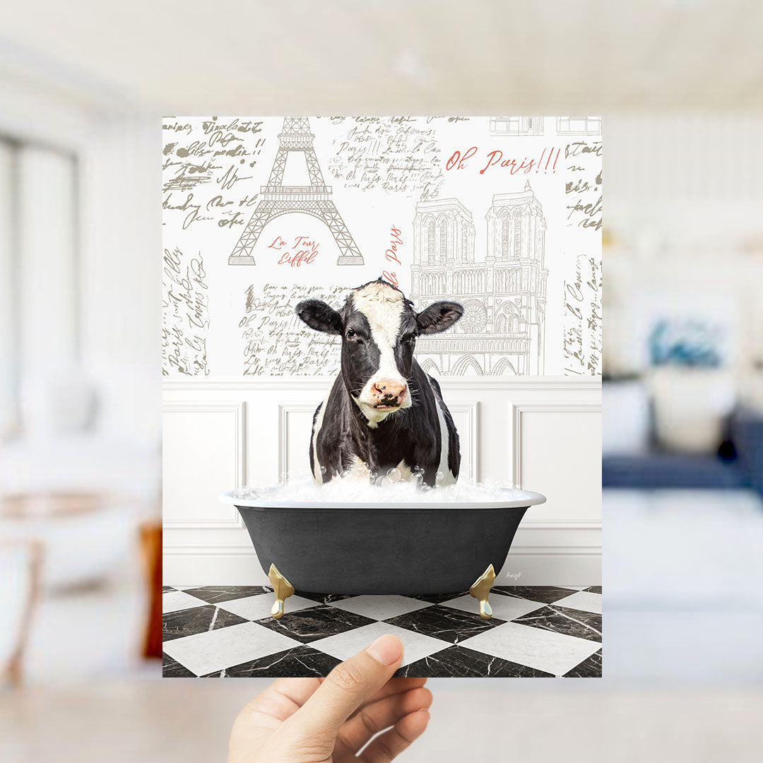 A black and white cow is sitting in a bathtub filled with water, surrounded by various Paris-themed elements such as the Eiffel Tower and other landmarks.