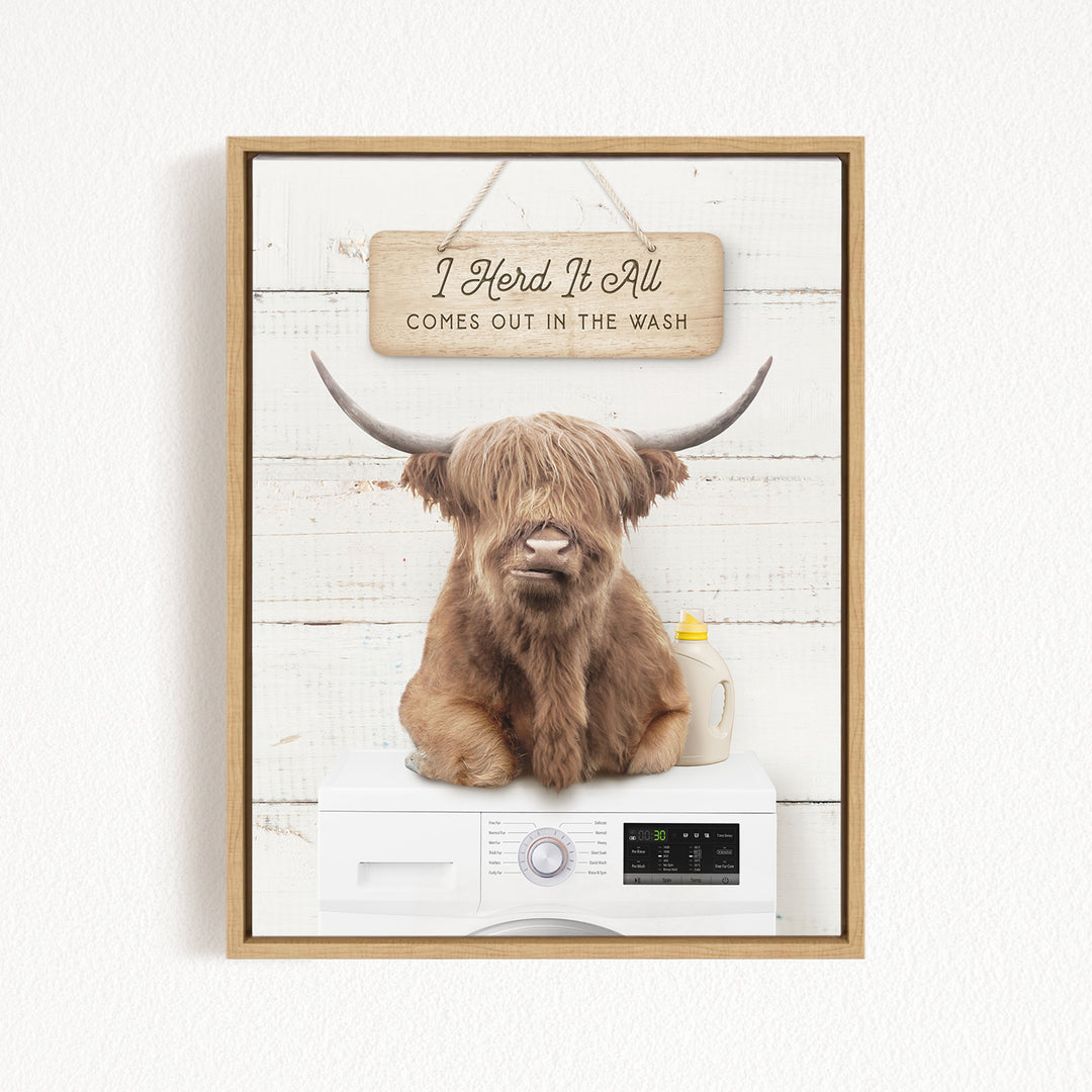 A framed image of a Highland cow with long horns sitting on top of a washing machine.