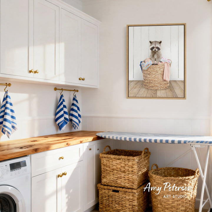 A laundry room with white cabinets, a wooden countertop, and a framed picture of a raccoon sitting in a basket.