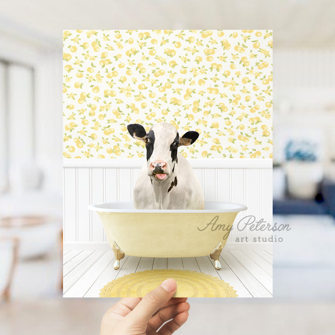 a person holding up a picture of a cow in a bathtub