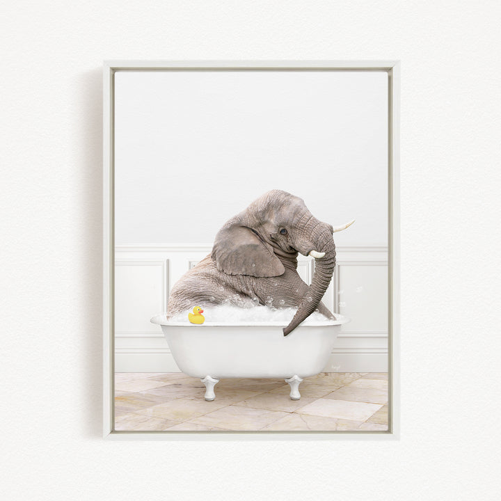 A gray elephant is sitting in a white bathtub filled with water, with a yellow rubber duck floating nearby.